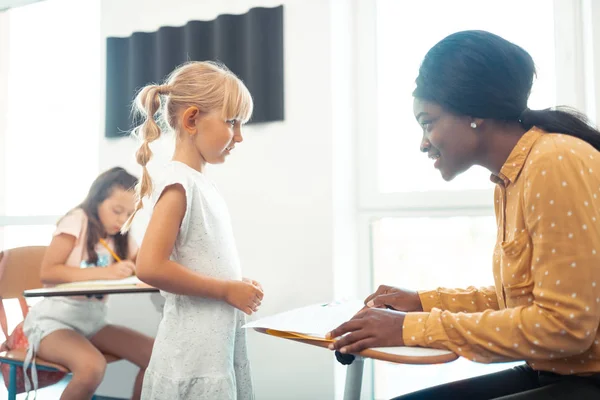 Beautiful blonde-haired pupil coming to teacher — Stock Photo, Image