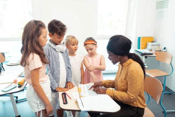 Girls and boy standing near their teacher telling them test results — Stock Photo, Image