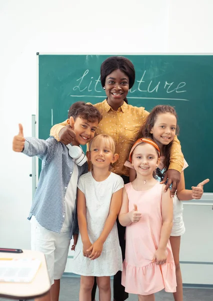 Children feeling truly happy standing near their kind loving teacher