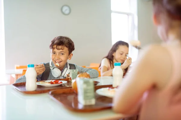 Tmavovlasý hoch s úsměvem na obědě s spolužáky — Stock fotografie