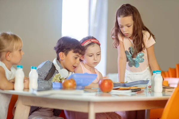 Niedlichen Mädchen und Jungen Blick auf den Zeitplan sitzen in der Kantine — Stockfoto