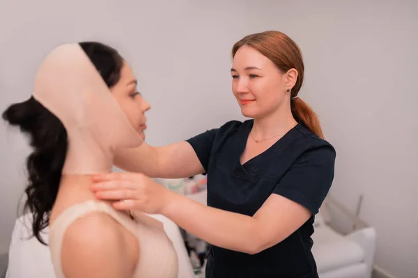 Krankenschwester in Uniform hilft Klient mit Verband im Gesicht — Stockfoto