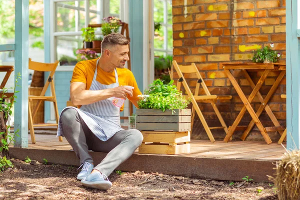 Knappe Bloemist het verzorgen van bloemen in een plantenbak. — Stockfoto