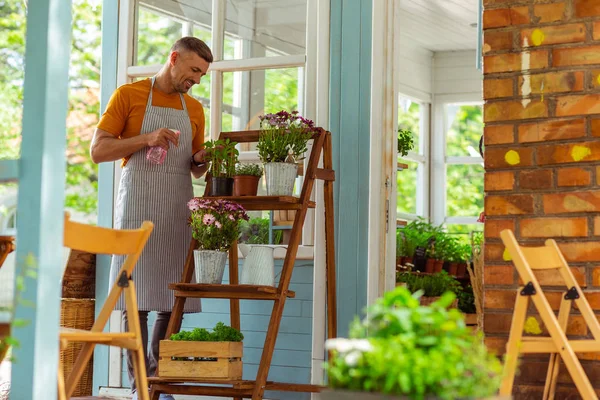 Fröhliche Floristin, die alle Pflanzen nach draußen streut. — Stockfoto