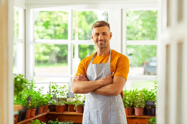 Floristería sonriente de pie frente a las plantas . —  Fotos de Stock