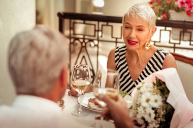 Sarışın saçlı eşi kocası ile romantik bir akşam yemeği yerken gülümseyen