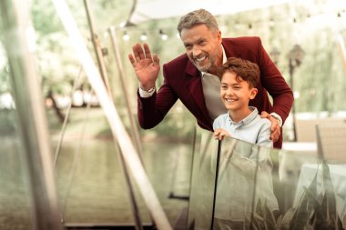 Baba ve oğul, restoranına gelen anneyi görerek el sallıyor