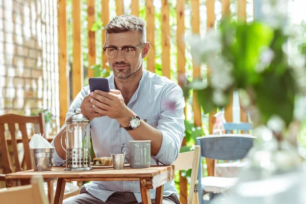 Pohledný muž, který čte novinky na telefonu. — Stock fotografie