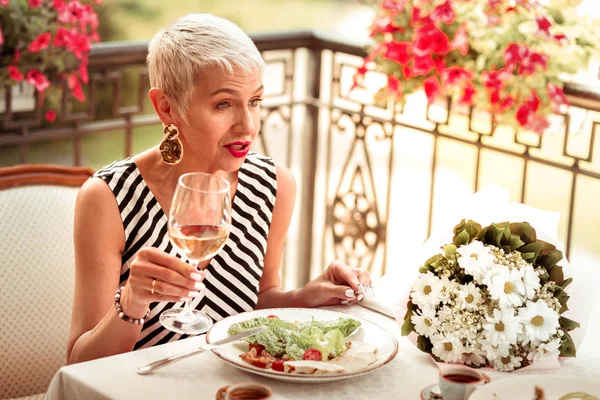 Femme mûre assise à la table près des fleurs parlant à son mari — Photo