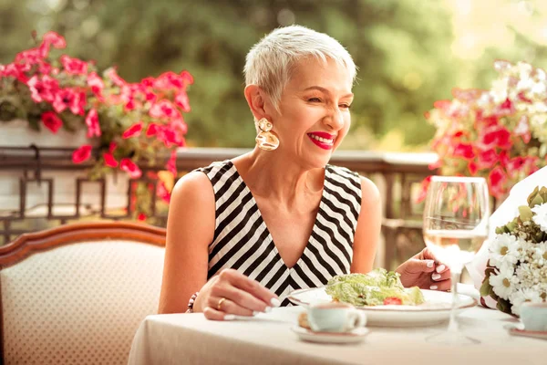 Dospělá blonďatá žena, která se směje, když večeří s manželem — Stock fotografie
