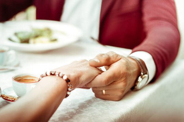 Close up of loving husband wearing watch touching hand of his wife