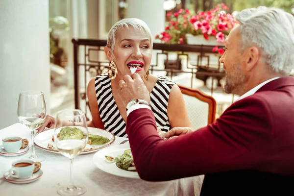 Fürsorglicher bärtiger Ehemann gibt seiner Frau etwas Salat — Stockfoto