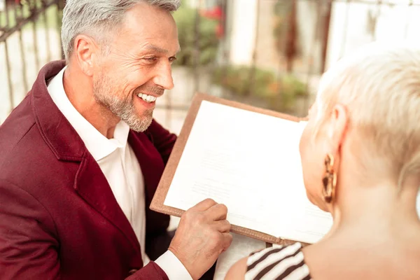 Чоловік посміхається, розмовляючи з дружиною перед замовленням в ресторані — стокове фото