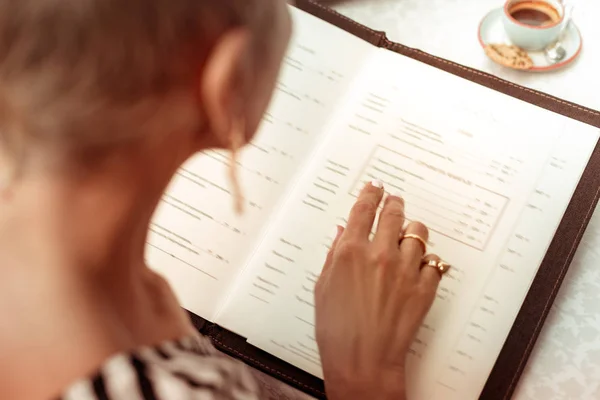 Frau mit schönen Ringen liest Speisekarte im Restaurant — Stockfoto