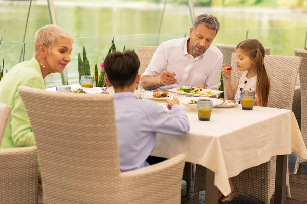 Dziadkowie rozmawiają z dziewczyną i chłopcem podczas śniadania — Zdjęcie stockowe