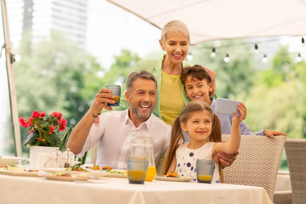 Carino ragazza dai capelli scuri facendo selfie con fratello e nonni — Foto Stock