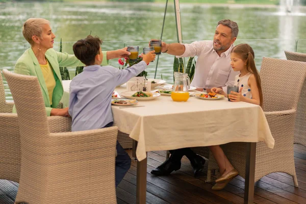 Nonni e il loro ragazzo e ragazza mangiare succo d'arancia per pranzo — Foto Stock