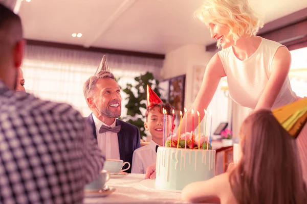 아들을위한 생일 케이크를 넣는 물결 모양의 머리를 가진 아름다운 여자 — 스톡 사진