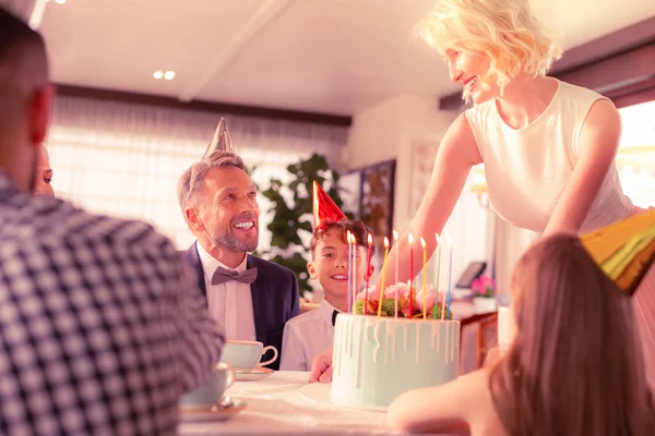 息子のための誕生日ケーキを入れて波状の髪を持つ美しい女性 — ストック写真