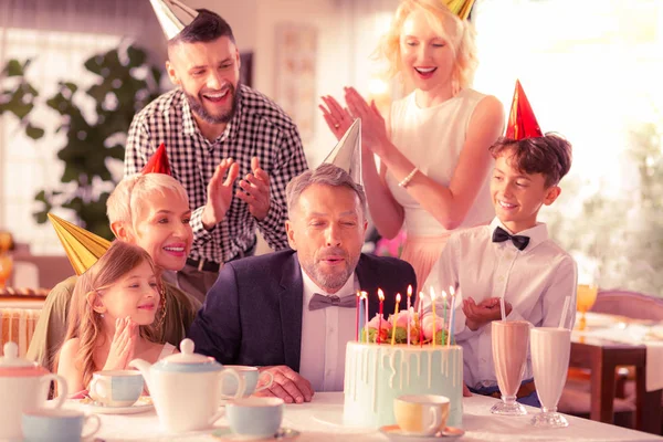 Aged man celebrating birthday with daughter and grandchildren