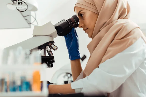 Έξυπνη έξυπνη γυναίκα που μελετά δείγματα μέσω του μικροσκόπιο — Φωτογραφία Αρχείου