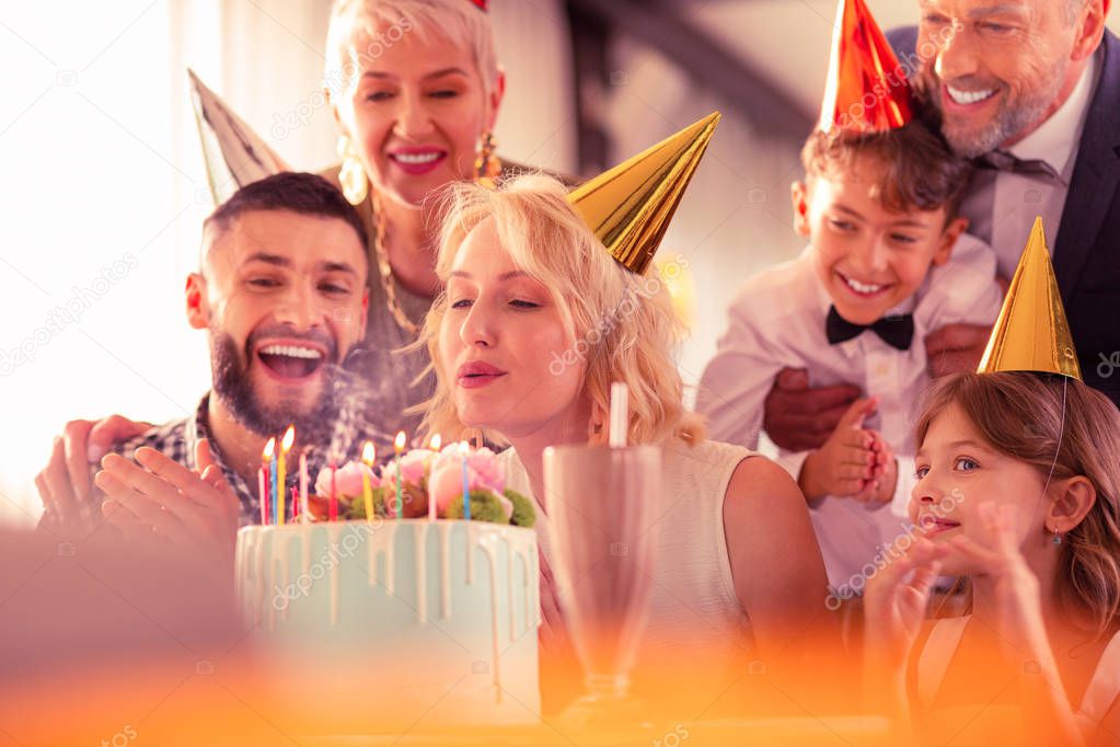Family feeling excited while birthday woman blowing candles