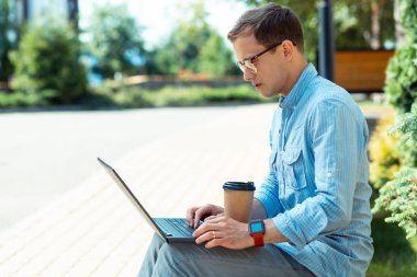 Dizüstü bilgisayarda çalışan ve kahve içen akıllı saat giyen freelancer