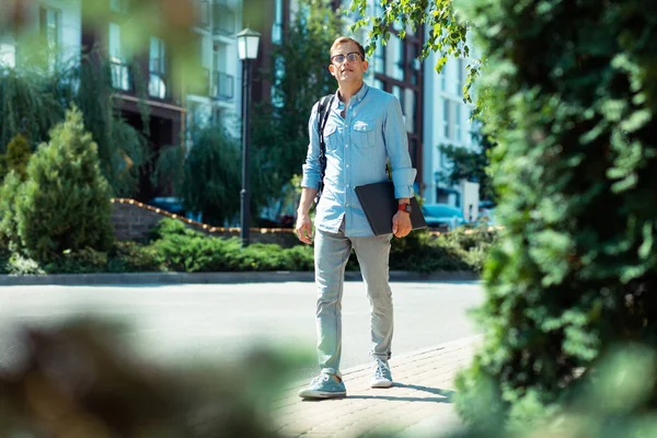 Hombre con reloj inteligente caminando a la oficina con el ordenador portátil en las manos —  Fotos de Stock