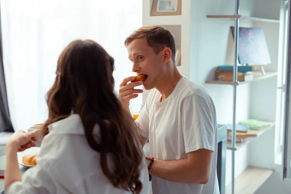 Marito dagli occhi azzurri mordere mela mentre fa colazione con la moglie — Foto Stock