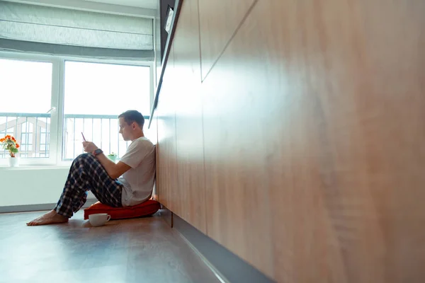 Freelancer sentado no chão perto da janela e lendo e-mail — Fotografia de Stock