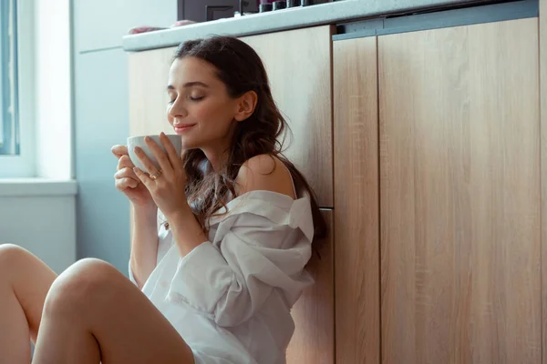 Lockig kvinna luktar kaffe medan du har frukost — Stockfoto