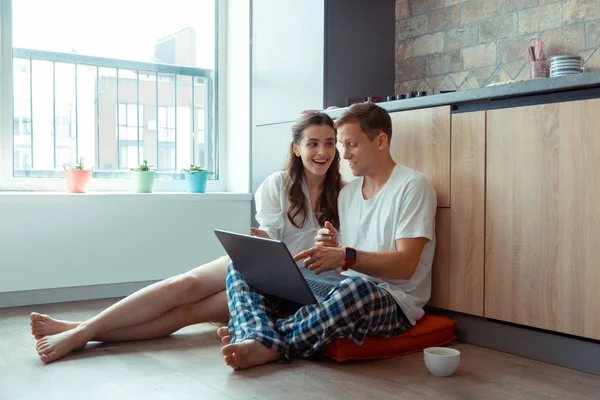 Casal falando enquanto faz compras online sentado no chão — Fotografia de Stock