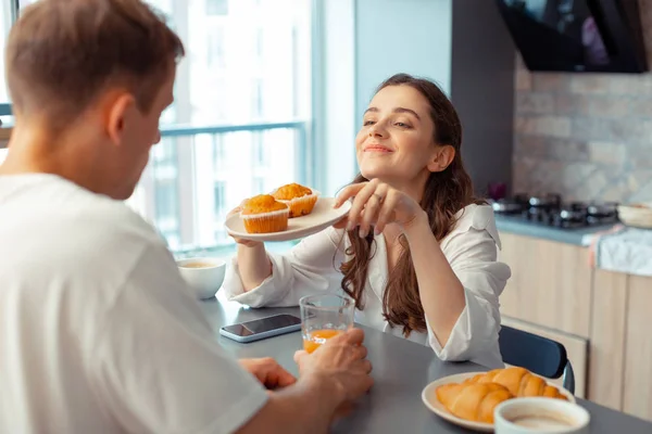 Liefdevolle zorgzame vrouw geven muffins voor man in de ochtend — Stockfoto