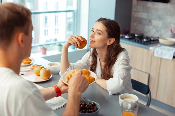 Mörkhårig man ger croissanter för fru äter äpple — Stockfoto