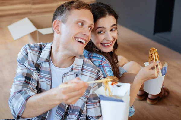 Pareja sonriente disfrutando fideos después de desempacar cosas —  Fotos de Stock