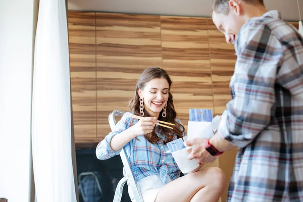 Casal alegre comer macarrão takeaway enquanto se move para novo apartamento — Fotografia de Stock