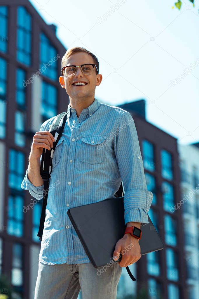 Businessman holding laptop smiling while walking to office