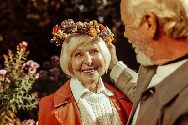 Пожилая женщина в цветочном венке и улыбается мужу . — стоковое фото