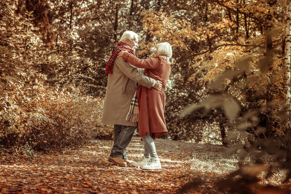 Счастливый старший мужчина обнимает свою жену в парке
.