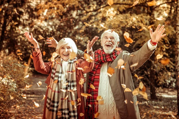 Feliz pareja de ancianos lanzando hojas de otoño . — Foto de Stock