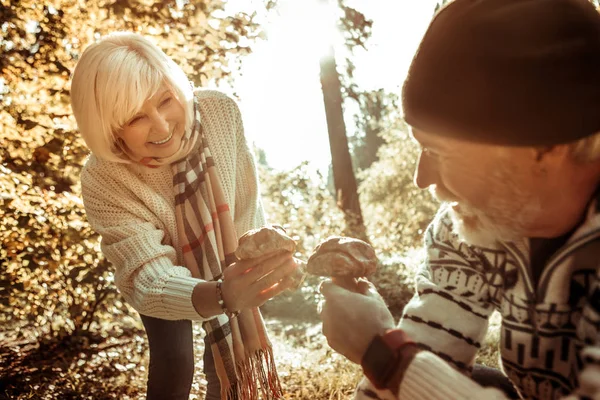 Glückliche Seniorin sammelt mit ihrem Mann Pilze. — Stockfoto