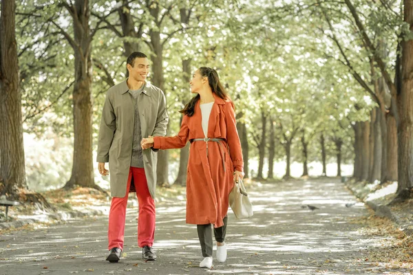 Приємна молода пара тримає руки під час прогулянки — стокове фото