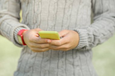 Sıcak gri kazak adam aktif bir akıllı telefonda mesajlaşma