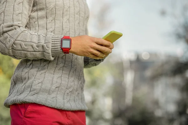 Hombre ocupado en pantalones de color rojo brillante y suéter gris que tiene reloj electrónico —  Fotos de Stock