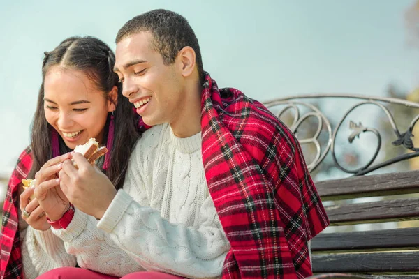 Pareja agradable contento comiendo deliciosos sándwiches en un aire fresco —  Fotos de Stock