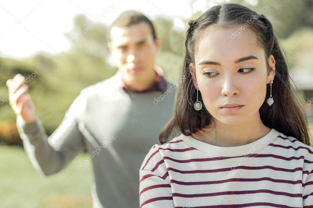 Upset dark-haired woman being tired of her jealous boyfriend