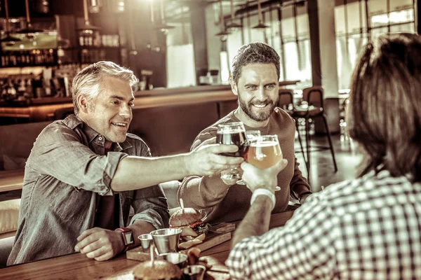Позитивные восторженные мужчины касаются стаканов с пивом — стоковое фото