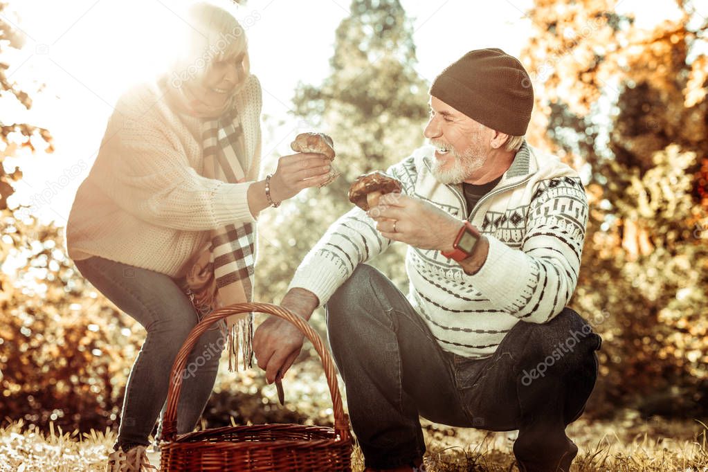 Smiling husband and wife gathering mushrooms together.