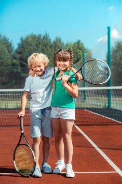 Tenis oynadıktan sonra mutlu hissederken erkek ve kız kardeş sarılma