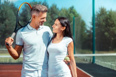 Yakışıklı kocasına bakan koyu saçlı karısı Işınıyor